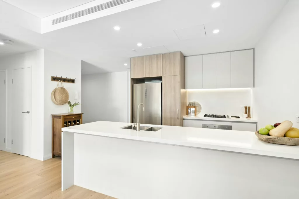 Spacious white kitchen with lengthy island and sink